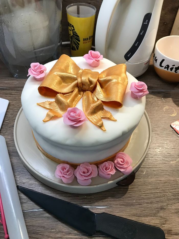 Weiße Fondanttorte mit goldener Schleife und rosa Zuckerrosen